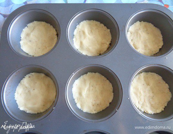 Выложить масляную крошку в форму для маффинов и аккуратно распределить руками по дну, я еще пальцами как бы утрамбовала.

Поставить выпекаться основу в предварительно разогретую до 180°С духовку.