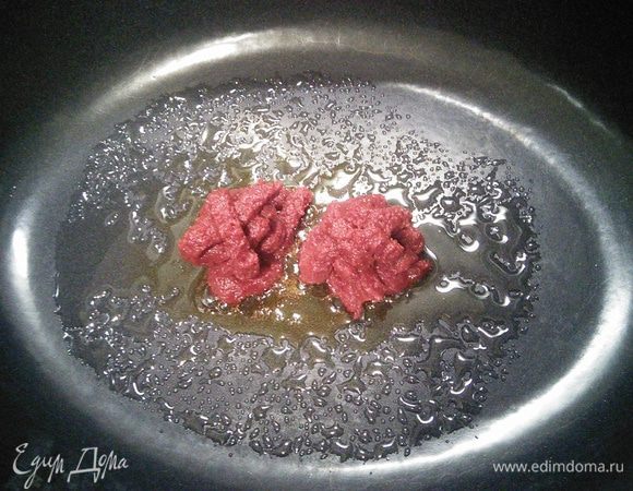 В емкость, в которой вы будете запекать мясо, всыпать сахарную пудру и закарамелизировать, добавить томатную пасту, перемешать и обжарить до золотисто-коричневого цвета. Духовку разогреть до 200°С.