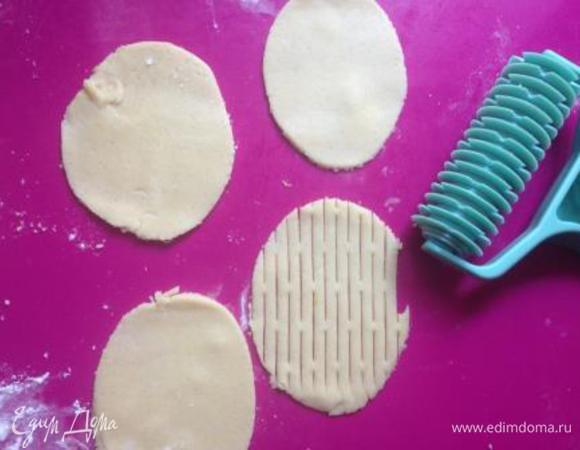 Вторую часть теста раскатать и вырезать круги. Каждый круг при помощи скалки превратить в овал. Немного отступив от края, прокатать ролик по тесту вдоль. Если вы не являетесь счастливым обладателем данного гаджета, можно просто нарезать тесто на тонкие полосочки и уложить крест-на-крест, в виде решетки.