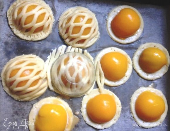 Аккуратно раскрыть тесто и уложить образовавшиеся решетки на половинки персиков, скрепив верхушки с основами, слегка прижав тесто по краям. Круглой выемкой подравнять изделия, чтобы получились аккуратные круги.
