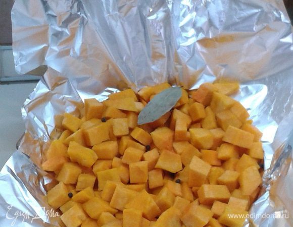 Очищенную тыкву порезать кубиками, добавить лавровый лист и перец горошком.  Положить в жаропрочную форму, покрытую фольгой. Запекать в духовке 25-30 минут, пока тыква не станет мягкой. Креветки опустить в кипяток, после закипания воды поварить их в течение 1 минуты.