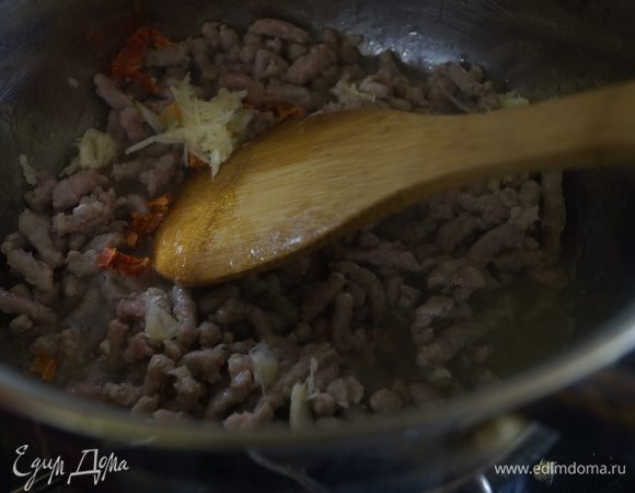Фарш обжариваем в толстодонной кастрюле на растительном масле. Добавляем чеснок, натертый на терке и мелко рубленный перец чили.