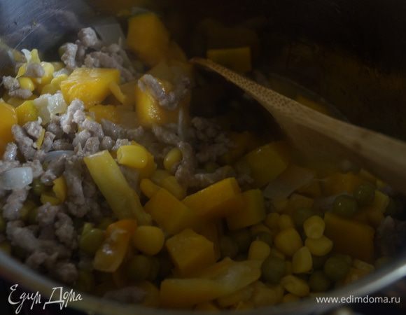 Добавляем к фаршу обжаренные овощи с тыквой, зеленый горошек и кукурузу. Заливаем овощным бульоном. Солим, перчим и перемешиваем. Готовим еще около 20-25 минут.