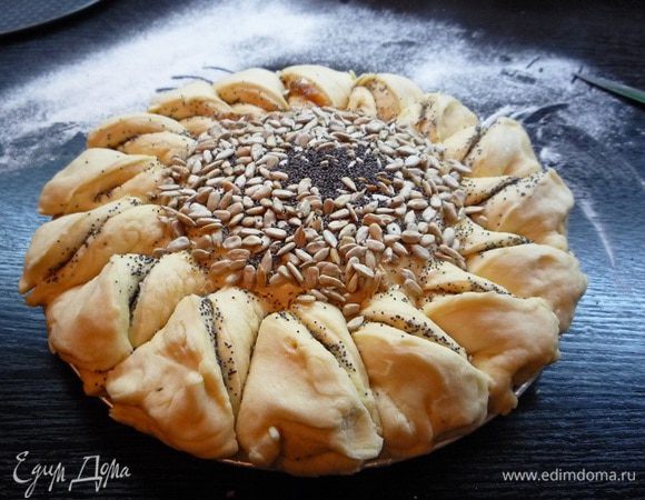 Центр пирога смазываем растопленным сливочным маслом, посыпаем семечками и маком. Смазываем края пирога взбитым яйцом.