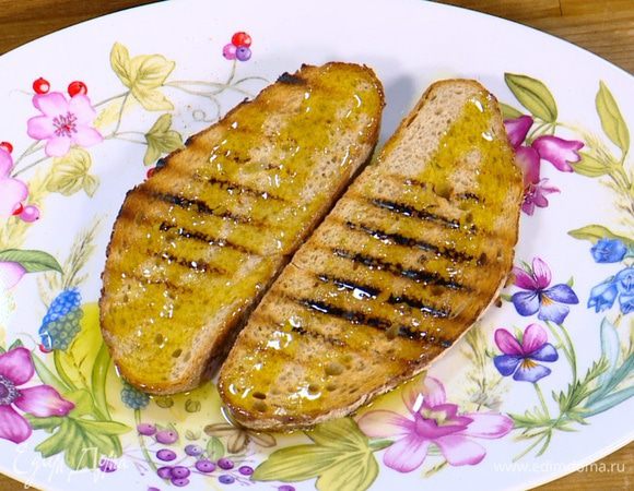 Разогреть сковороду-гриль и подсушить хлеб с двух сторон, затем снять со сковороды и сбрызнуть оливковым маслом.