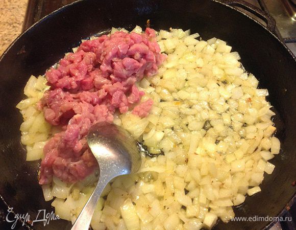 В глубокой сковороде на растительном масле довести лук до прозрачного цвета, затем добавить мясо. Прожарить минут пять на среднем огне.