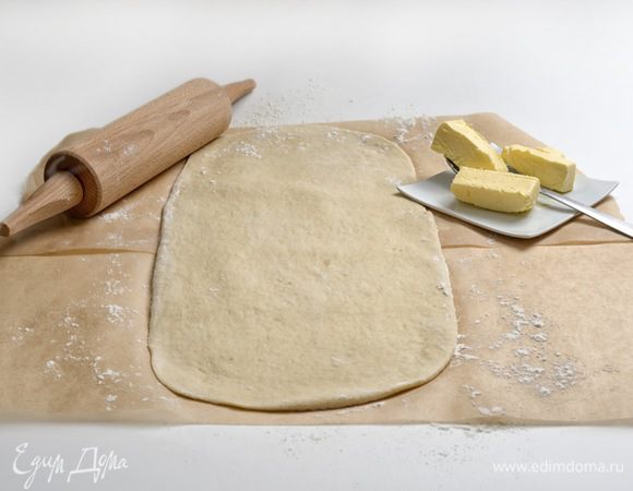 Тесто переложить на лист бумаги для запекания и раскатать в прямоугольник. Оставшееся сливочное масло разделить на 3 части (масло должно быть мягким).

