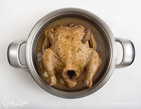 Как только цыпленок покроется золотистой корочкой со всех сторон, достать его из кастрюли, слить из кастрюли масло так, чтобы осталось совсем на донышке, и бросить на дно 5 раздавленных долек чеснока, после чего влить туда же пол-литра горячей кипяченой воды. Довести воду до кипения добавить соли и сахара по вкусу так, чтобы получился солено-сладкий бульон. Затем поместить в бульон цыпленка, накрыть крышкой и потомить минут 20.
