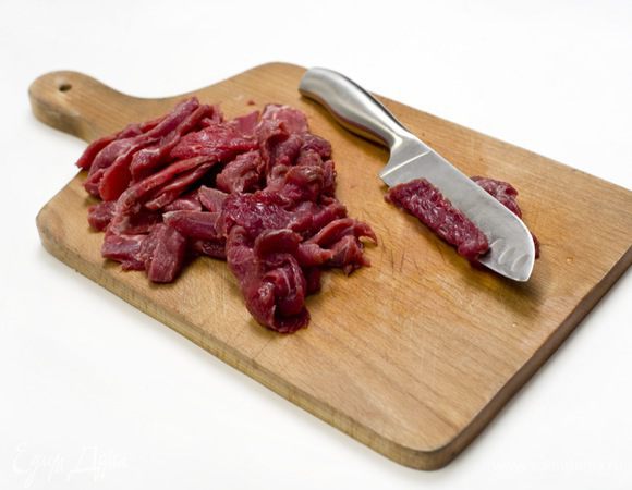 Мясо нарезать на тонкие полоски. Для того, чтобы это было легче сделать, можно предварительно на 30 минут положить его в морозилку.

