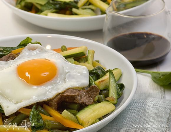 На дно глубокой тарелки выложить рис, в центр поместить обжаренное мясо, по кругу разместить овощи. Полить всё кунжутным маслом и соевым соусом, посыпать  перцем чили и кунжутными семечками. Сверху выложить яичницу глазунью. Приятного аппетита!