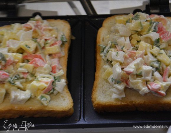 Сэндвичницу разогреть. Уложить хлеб для тостов. Выложить начинку, — не жалеем. И накрыть верхним куском хлеба.