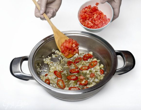 Помидоры полминуты бланшировать в кипящей воде, затем снять кожицу, мелко порезать, добавить к луку, чесноку и  перцу чили. Тушить 10 минут.
