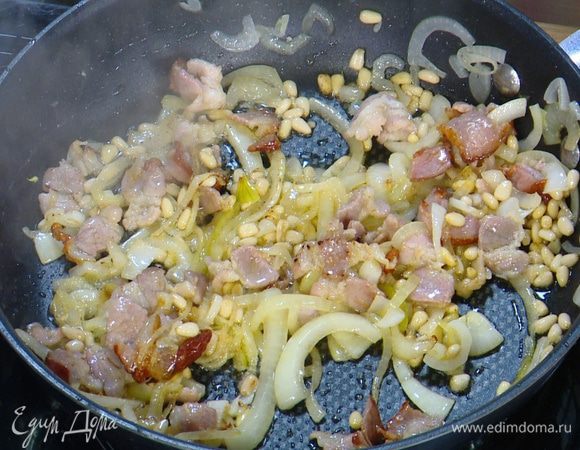 Кедровые орехи всыпать в сковороду с луком и беконом и, непрерывно перемешивая, обжаривать все, пока орехи не приобретут золотистый оттенок.