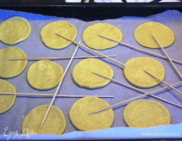 С помощью формы или стакана вырезаем кружочки. Я сразу начала выкладывать кружки на противень. Но можно продолжить работать с тестом на столе, оно не прилипает к поверхности и хорошо держит форму. Для моих "подсолнухов" сразу подложила палочки. Это тоже можно сделать после выпечки печенья. 