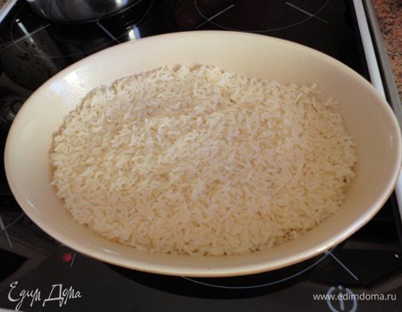 Форму смазать небольшим количеством масла (1 ст.л.), выложить рис и полить его половиной стакана бульона из половины кубика. 
