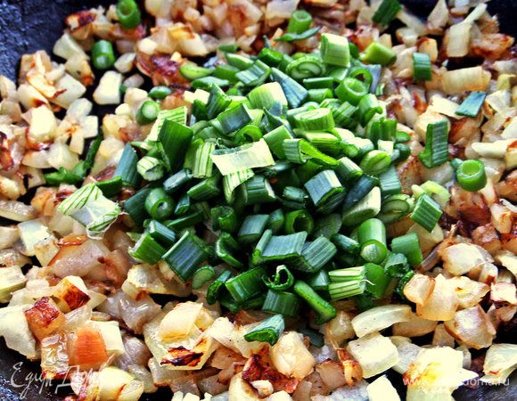 К обжаренному репчатому луку высыпать измельченный зеленый лук.