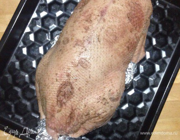 Пока фаршируем гуся начинкой, разогреваем духовку до 220°С. Гуся зашиваем или закрепляем край зубочистками (кому как удобнее). Концы ножек и крыльев обернуть фольгой, обязательно ножки перевязать бечевкой. Гуся натереть солью и перцем, а затем положить на смазанный жиром или маслом противень. Запекать 30-35 минут, после чего снизить температуру духовки до 180°С и готовить еще 2,5-3 часа, периодически поливая гуся его соком.