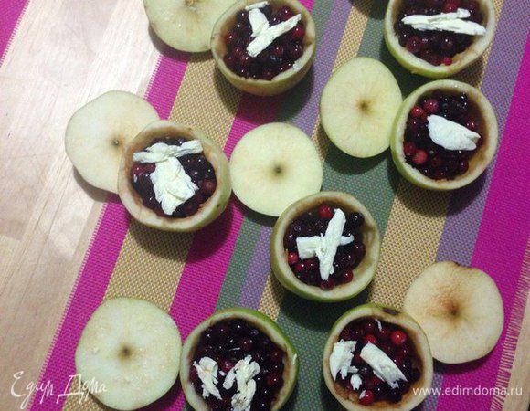 Вынуть гуся из духовки и дать постоять 20 минут. Пока гусь отдыхает, запекаем яблоки. Смешать в миске клюкву и ягодный сироп. Острым ножом снять с яблок «крышечки» и вырезать сердцевину, оставив тонкие стенки. Заполнить яблоки клюквенной смесью, сверху положить по кусочку сливочного масла и посыпать сахаром. Накрыть «крышечками» и запекать 20 минут при температуре 170°С до мягкости.