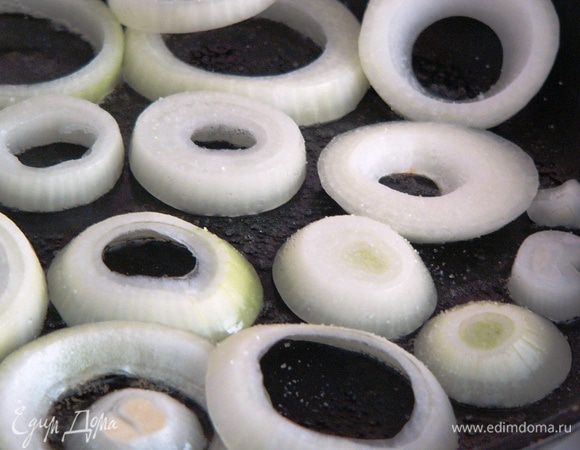 На сковороде разогреваем растительное масло. Укладываем кольца лука. Посыпаем сахаром и добавляем щепотку соли.