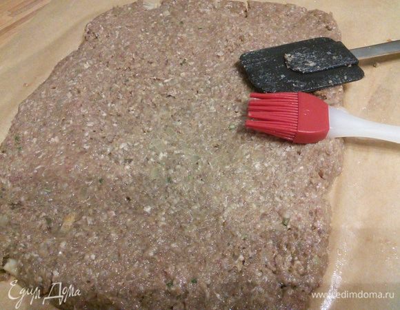 Застелим рабочую поверхность бумагой для выпечки. Про помощи кисточки смажем бумагу растительным маслом. Выложим на бумагу фарш, слегка сбрызнув растительным маслом, разровняем при помощи лопаточки в прямоугольник примерно 25*30 см.