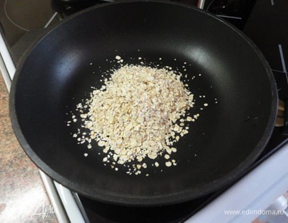 Две столовые ложки овсяных хлопьев выложить на сухую сковороду и подсушить в течение 1 минуты.