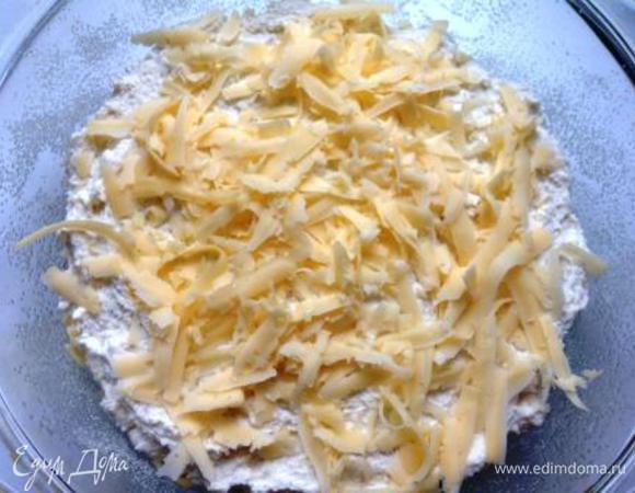 Выложить начинку на тесто, сверху распределить оставшееся тесто и присыпать оставшимся сыром.