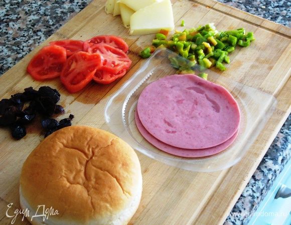 Когда у нас уже нашлась подходящая булочка (у меня была для гамбургеров), поищем в холодильнике подходящие продукты, чтобы сформировать бутерброд. У меня оказались оливки, ветчина, зеленый перец, помидор. Сыр назовем в данном случае обязательным ингредиентом. 

И сразу включаем разогреваться духовку!