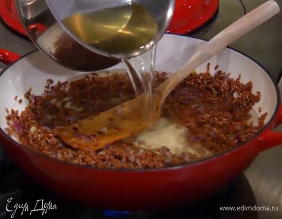 Когда рис станет блестящим, влить горячий овощной бульон, так чтобы рис был покрыт жидкостью.