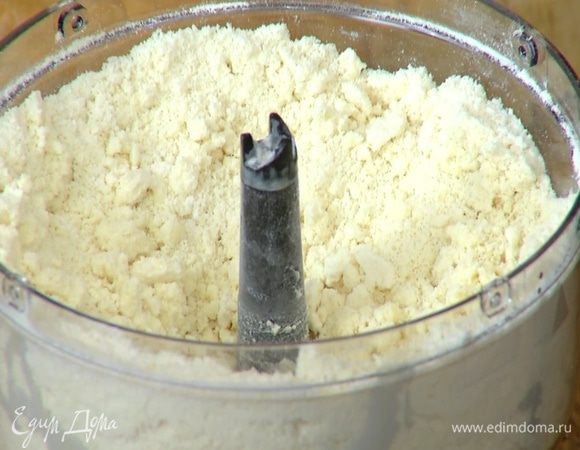 Предварительно охлажденное сливочное масло порубить кубиками, выложить в чашу блендера, добавить муку с разрыхлителем, соль и измельчить все в крошку.
