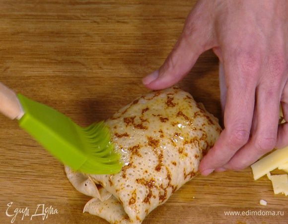 На край блинчиков выложить понемногу начинки, свернуть конвертиками и смазать со всех сторон оставшимся растопленным сливочным маслом.