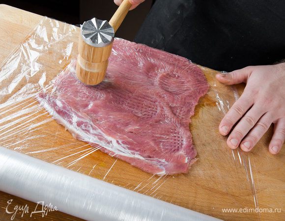 Корейку аккуратно разрезаем вдоль, но не до конца. Разворачиваем, накрываем пищевой пленкой и отбиваем молотком до одинаковой толщины, солим, перчим.
