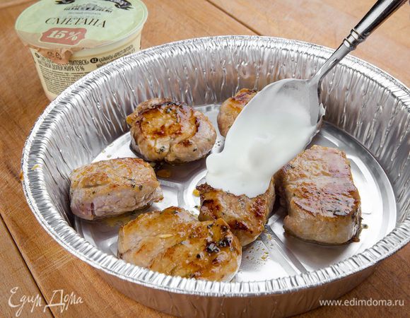 Дальше мясо раскладываем на противень, смазываем его сметаной.
