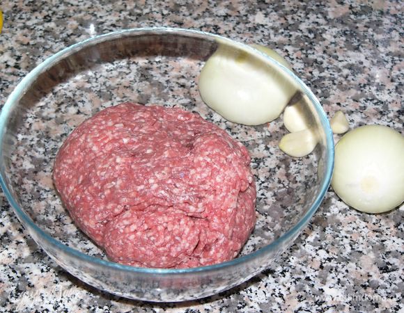 Начнем с котлет. Фарш переложить в большую миску. Луковицу и чеснок очистить и измельчить. Мелко порезать петрушку. 