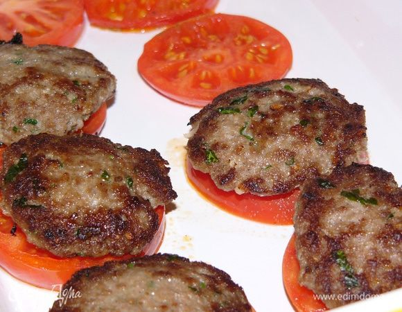 В форму для запекания выложите первым слоем помидоры. Сверху — котлеты. 