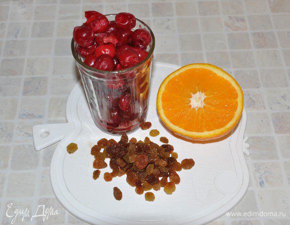 Вишню (не размораживая) и изюм помыть, половину апельсина нарезать на кружочки.