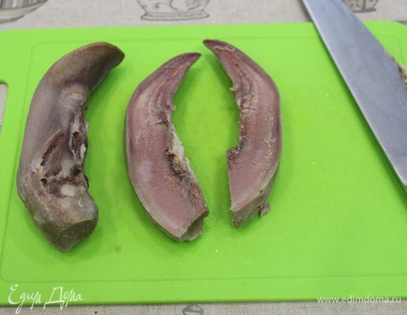 Отваренные свиные языки разрежьте вдоль.