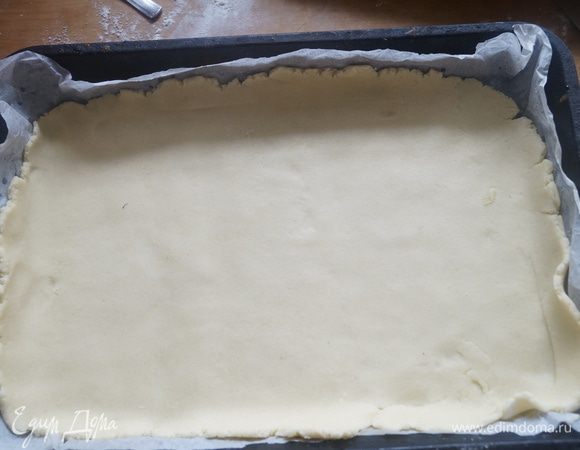 Тесто достать из холодильника и разрезать на 2 части (одну поменьше другую побольше. Меньшую часть раскатать в пласт толщиной 3-4 мм. Выложить в форму для выпечки застеленную пергаментом.