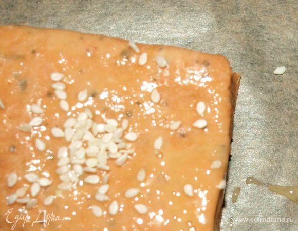 На припыленной мукой поверхности раскатываем тесто и режем на 12 квадратов. Перекладываем квадраты на противень или силиконовый коврик. Смазываем квадраты яйцом и посыпаем кунжутом.