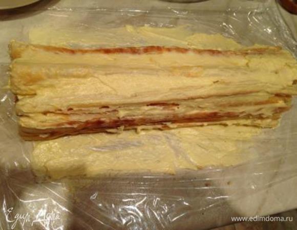 На столе расстелить пищевую пленку.
Выложить на нее слой из выпеченных полосок (штучки 4).
Смазать кремом.
Повторять слои до окончания ингредиентов.