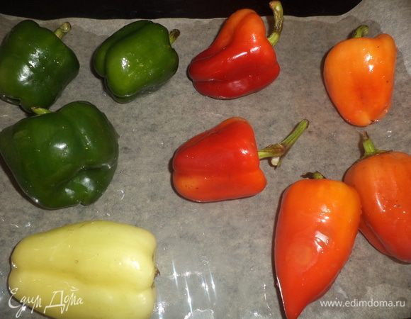 Духовку разогреть до 200°.
Стручки перца сбрызнуть растительным маслом, выложить на выстланный бумагой для выпечки противень. Запекать перец 20 минут, до почернения кожицы.