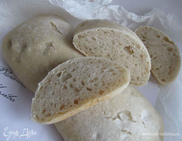 Разогреть духовку до 250 градусов. Выпекать с паром. Противни (один — для хлеба, другой — для воды) оставить в духовке во время разогревания духовки. Стенки духовки сбрызнуть из пульверизатора. Вынуть после разогрева противень для чиабатты, застелить его бумагой для выпечки, перенести заготовки с полотенца на противень. В нижний противень налить (аккуратно, пар!) примерно 300 мл кипятка. Выпекать при температуре 250 градусов в течение первых 15 минут, затем убавить температуру до 200 градусов и выпекать еще 15-20 минут, затем вставить в дверку духовки деревянную ложку (ручку деревянной лопатки), чтобы образовалась небольшая щель (необходимо избавиться от излишков пара и создать вентиляцию для того, чтобы образовалась хрустящая корочка) и еще дать чиабатте пропечься 3-5 минут.
При постукивании по нижней части хлеба должен быть пустой звук. Можно оставить в выключенной духовке на решетке, покрытой бумагой для выпечки, еще минут на 7-10. В любом случае следите за временем — духовки у всех разные. Вынуть, положить на решетку до полного остывания. 
Приятного аппетита!