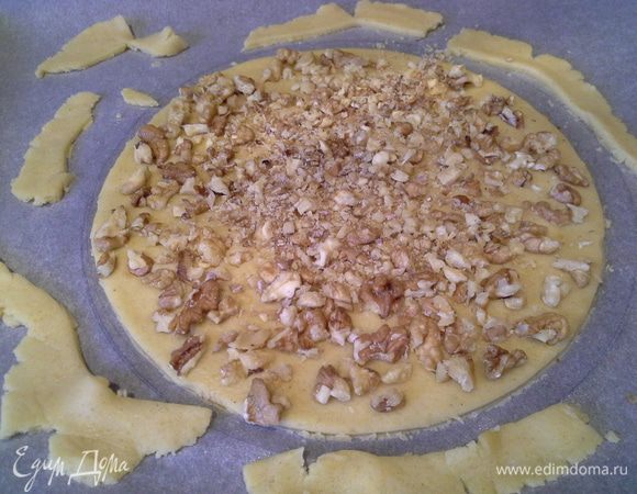 Раскатать 1 часть теста и вырезать корж (я крышкой), сверху посыпать грецкие орехи, вдавить рукой в тесто.