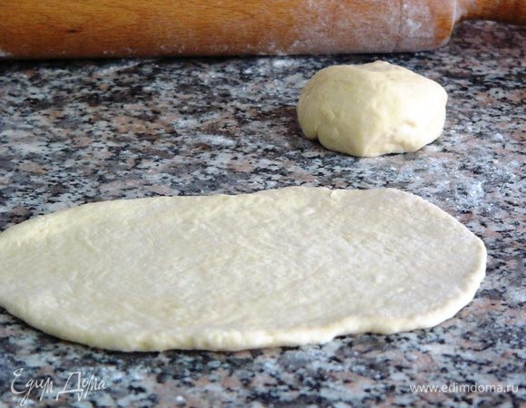 Берем по кусочку теста и, с помощью скалки, слегка раскатываем его в форме овала.