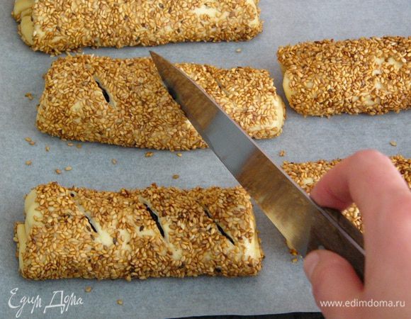 Подготовленные симиты выкладываем на противень, застеленный пекарской бумагой. С помощью острого ножа делаем сверху по три разреза.