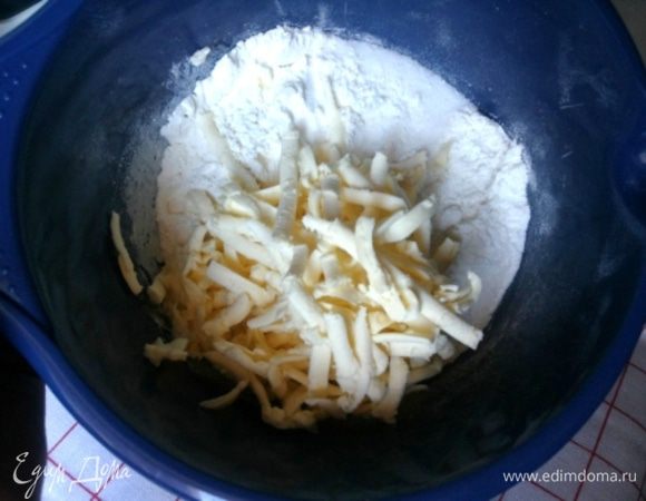 Муку смешиваем с сахаром и разрыхлителем. Добавляем натертое на крупной терке сливочное масло. Перемешиваем, должна получиться крупная крошка. Добавляем цедру апельсина.