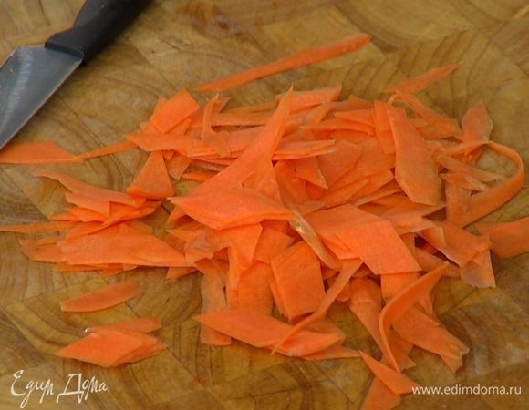 Морковь почистить и нарезать тонкими длинными полосками (можно воспользоваться овощечисткой), затем порезать полоски небольшими кусочками наискосок.