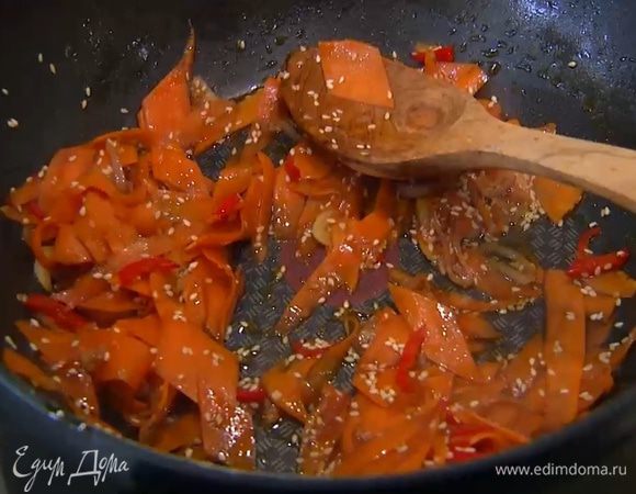 Разогреть в сковороде вок оливковое и кунжутное масло и обжарить шалот, чеснок и перец чили. Добавить морковь, всыпать кунжут, все перемешать и немного обжарить, затем влить соевый соус, все перемешать и еще немного обжарить. Снять вок с огня, влить оставшийся рыбный соус и еще раз все перемешать.