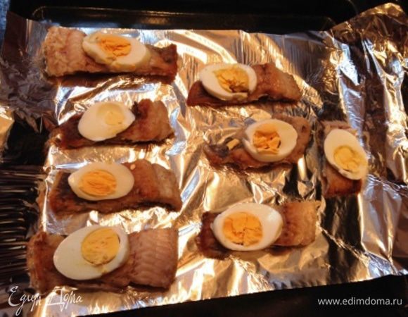 Помидор и сваренные яйца порезать вдоль.
Зелень нарезать мелко, сыр натереть на крупной терке.
На лист фольги или пергамента выложить рыбу.
На рыбу яйца.