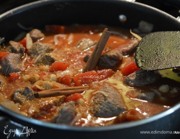 Влить на сковороду бульон, добавить баночный готовый, промытый под водой бараний горох нут, (баночка примерно размер стакана 250 мл), помидоры сливовидной формы, порезанные кубиками, сушеные абрикосы без косточек, имбирь свежий тертый, лимонная цедра и палочки корицы. Довести до кипения и затем вернуть кусочки ягнятины. Закрыть крышкой и тушить на медленном огне 1 час.  Снять крышку и готовить еще 20 минут до загустения соуса.