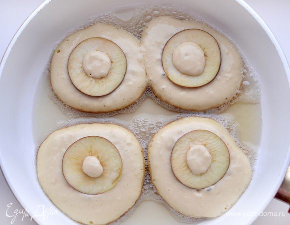 В сковороду влить растительное масло, хорошо прогреть на среднем огне. Выложить столовую ложку теста на сковороду, сверху положить колечко яблока, слегка вдавить в тесто.